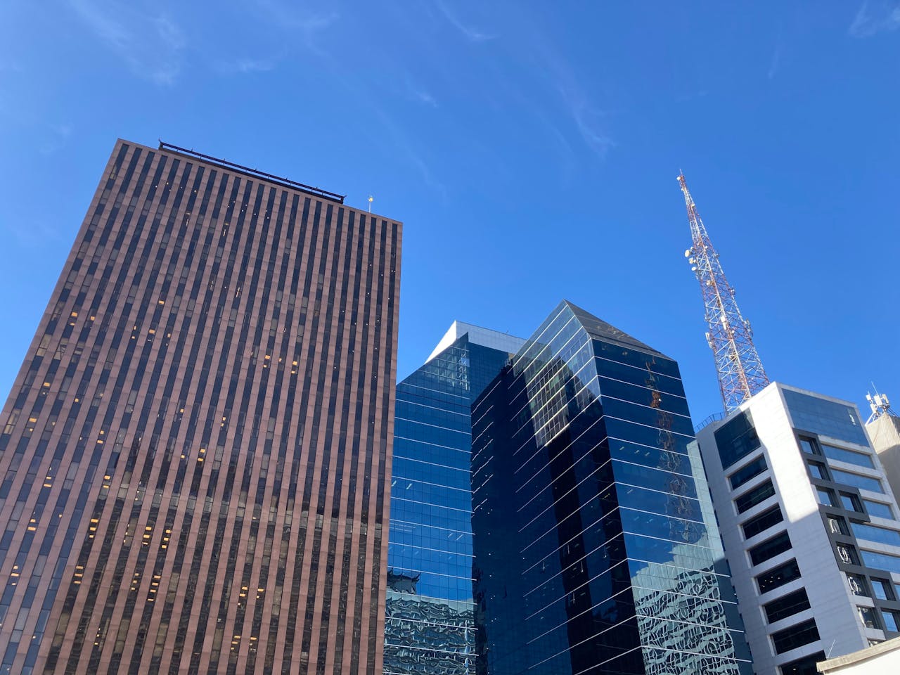 Low angle view of a cityscape featuring modern skyscrapers against a clear blue sky.